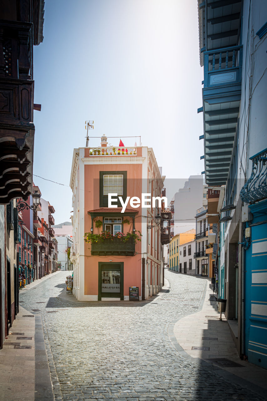 Empty alley amidst buildings in city against sky