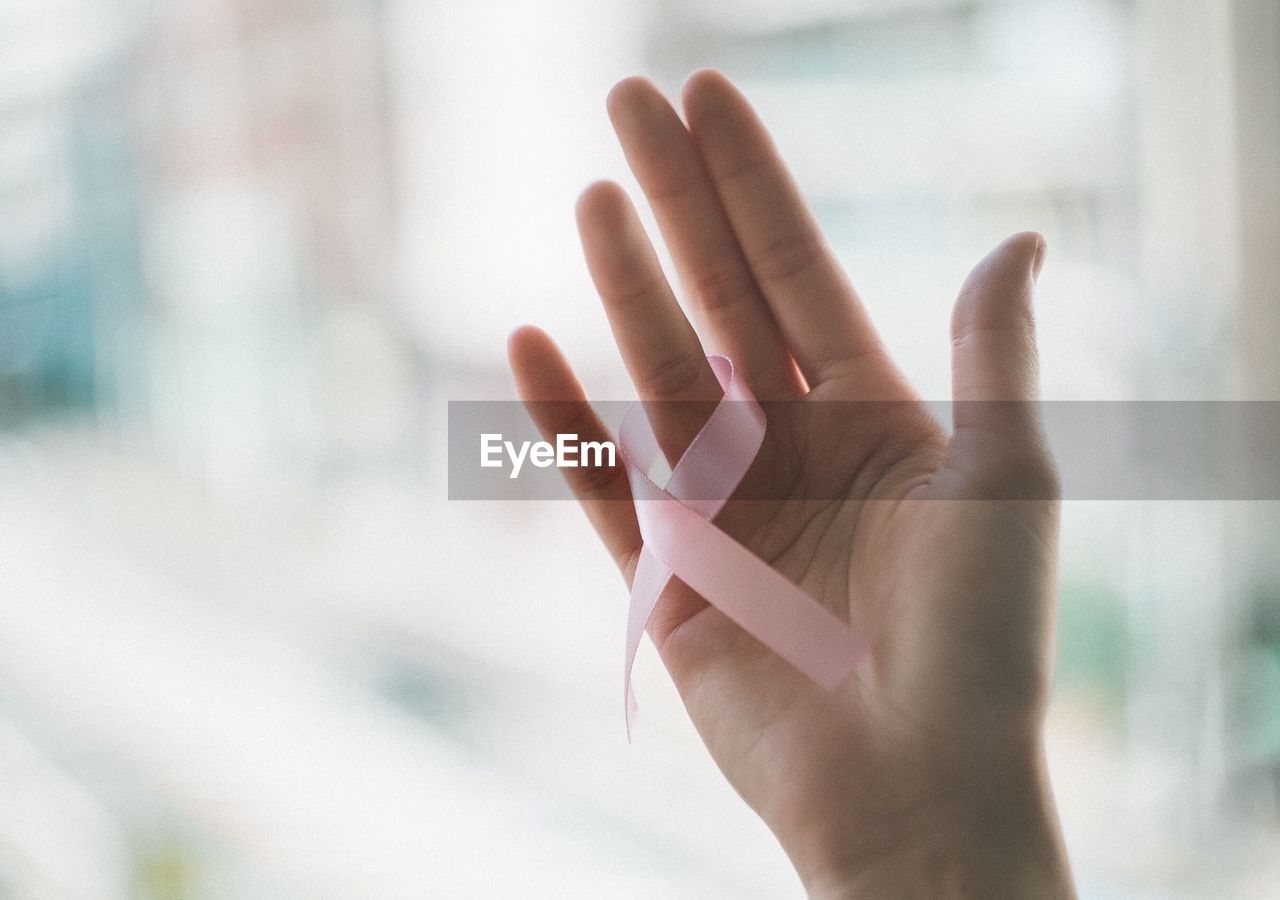 Close-up of woman hand and pink ribbon