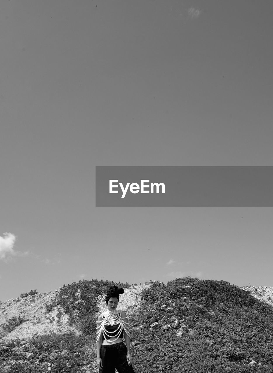 Rear view of woman standing on mountain against sky