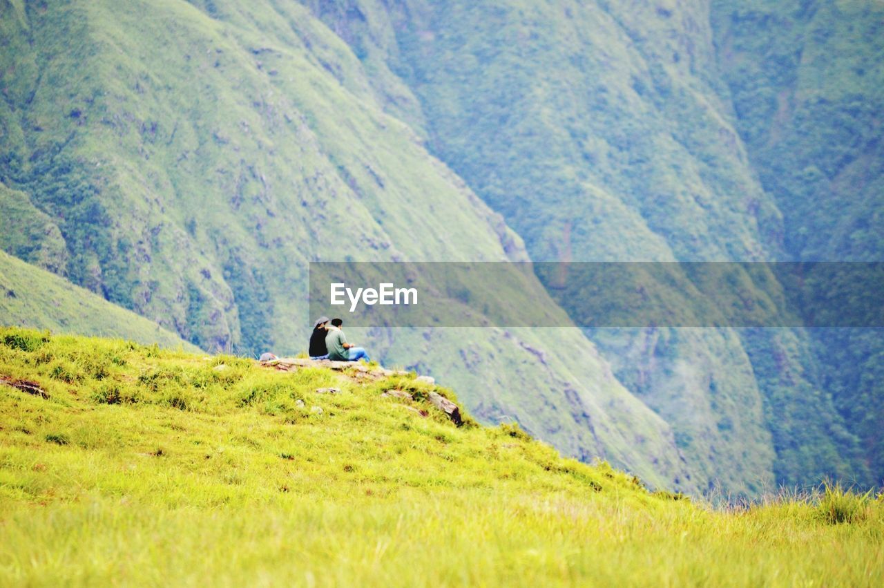 Distant view of people sitting against mountains