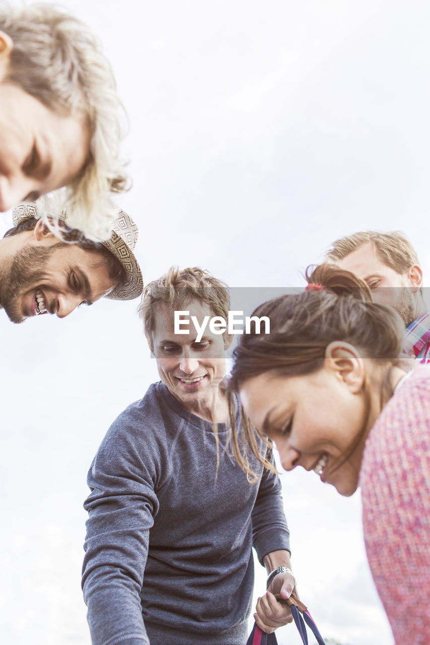 Low angle view of happy friends against sky