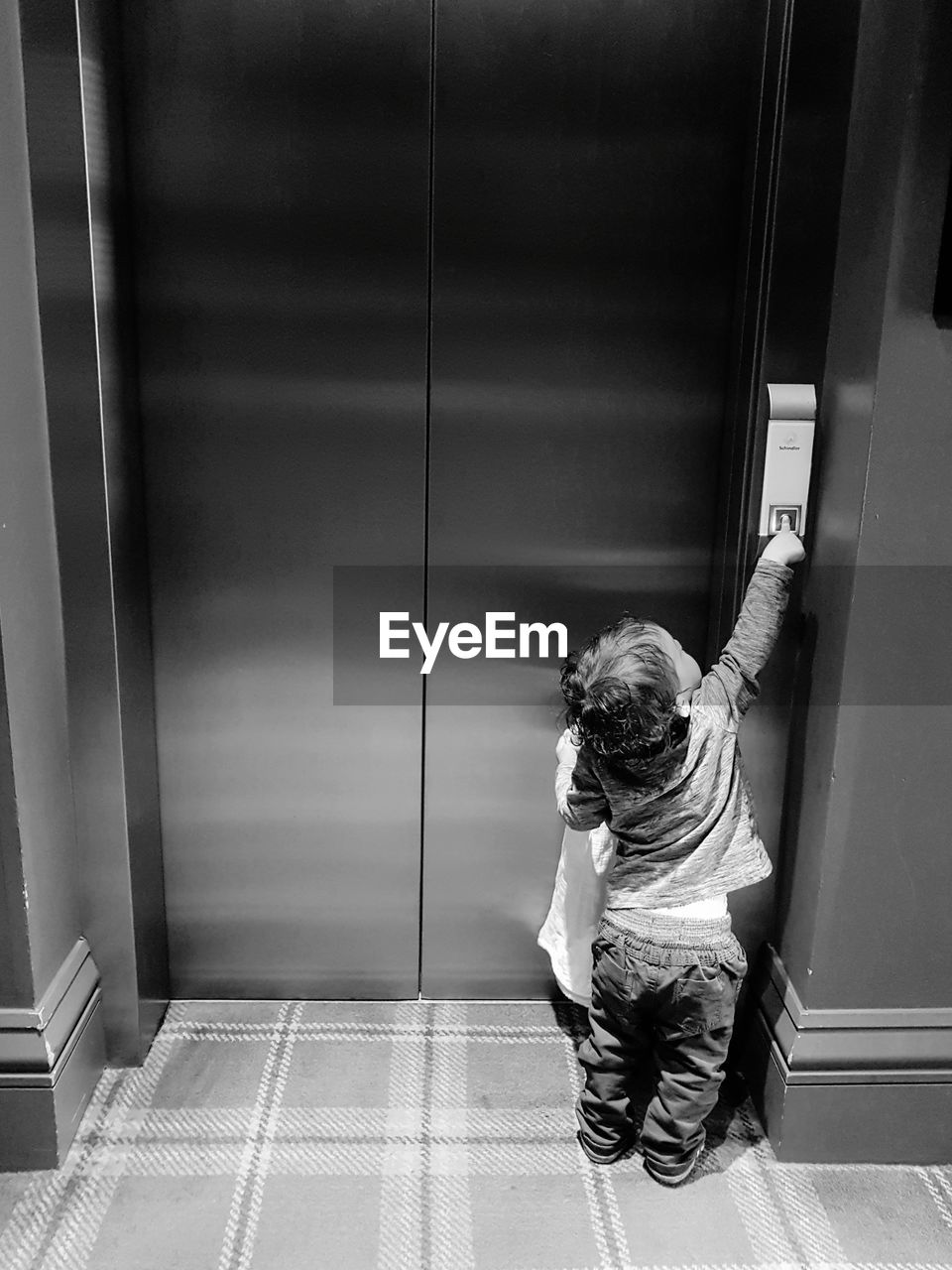 Rear view full length of boy pressing elevator button