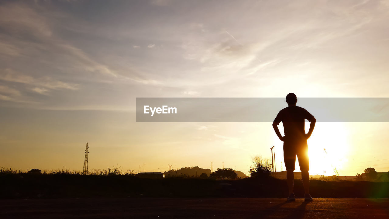 SILHOUETTE MAN STANDING ON SHORE AGAINST SKY DURING SUNSET