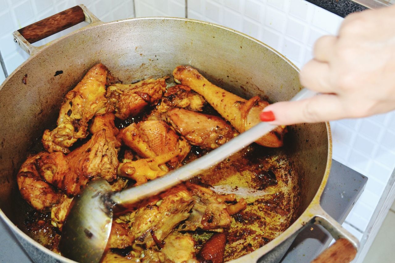 Cropped image of woman cooking chicken at domestic kitchen