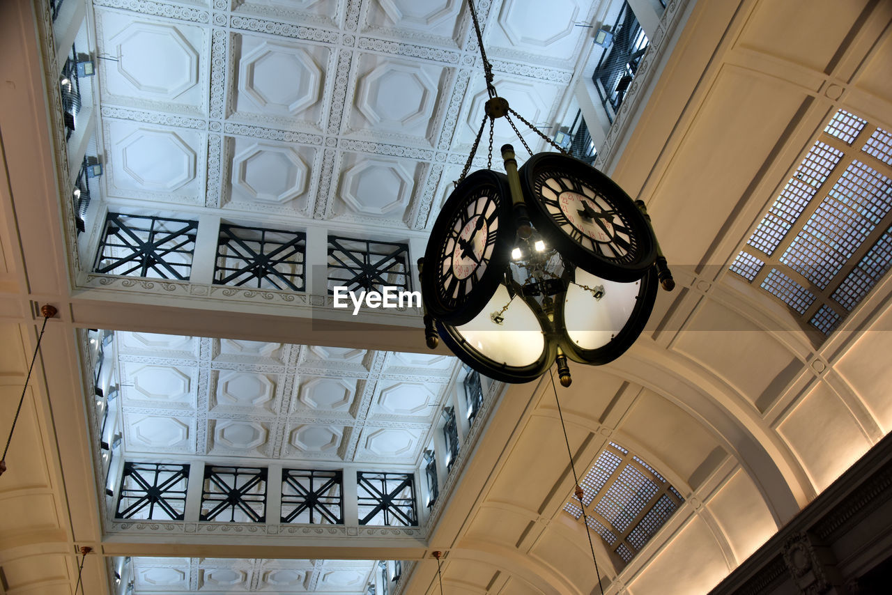 LOW ANGLE VIEW OF ILLUMINATED PENDANT LIGHT HANGING ON CEILING IN BUILDING