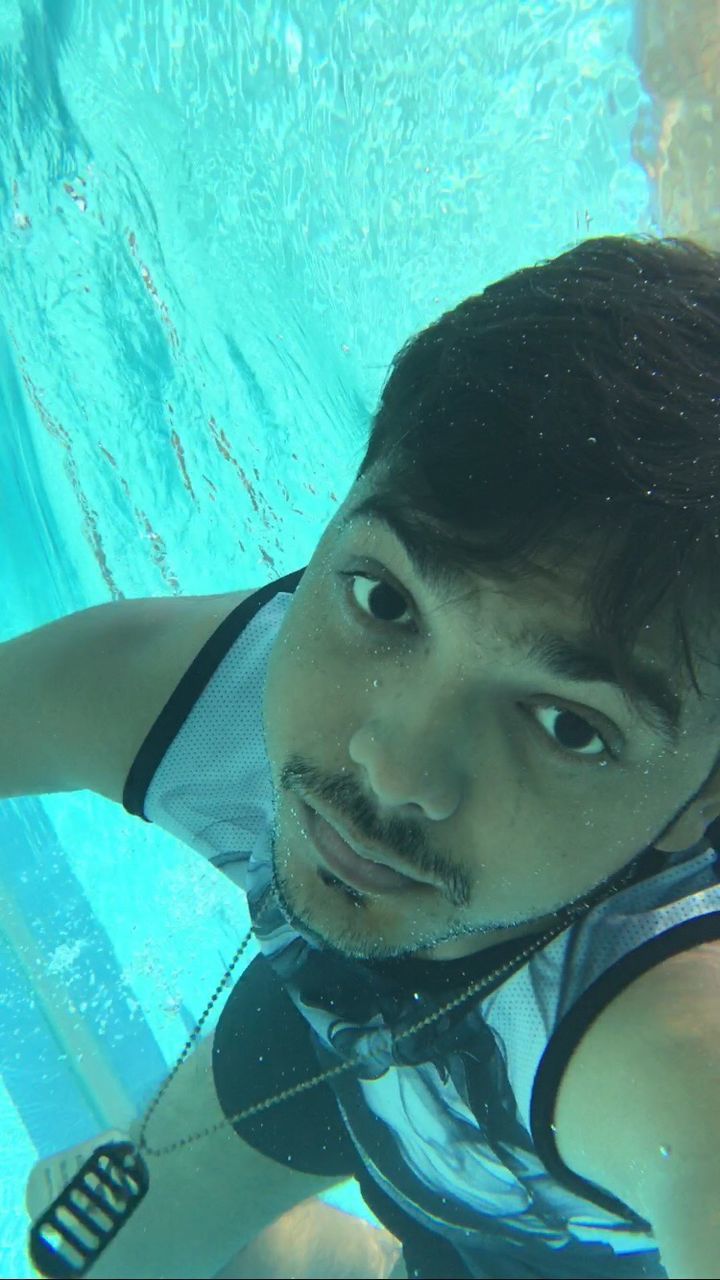 Close-up portrait of young man swimming in turquoise pool