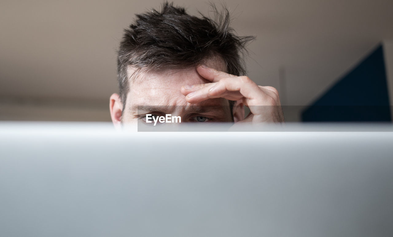 PORTRAIT OF MAN USING MOBILE PHONE IN LAPTOP