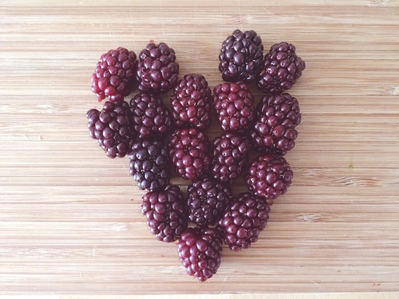 Directly above shot of black berries arranged in heart shape on table