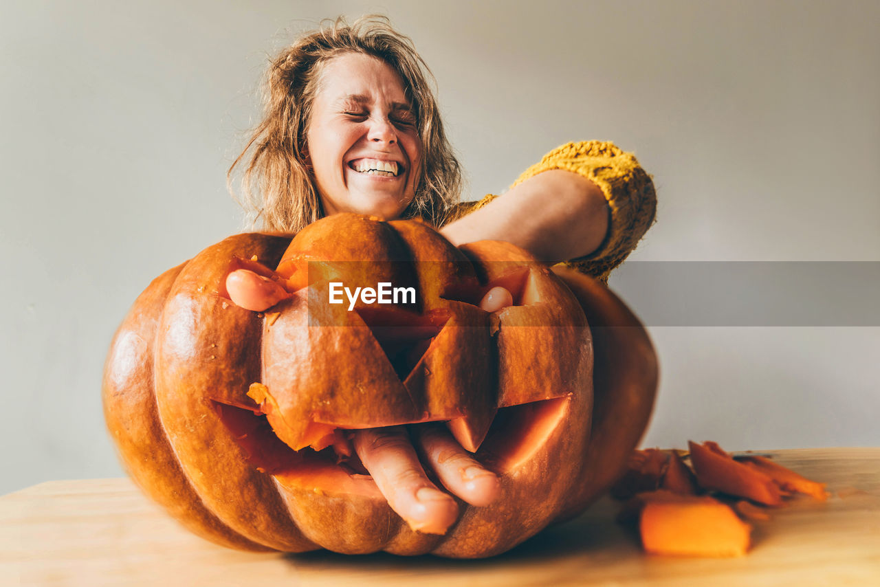 portrait of woman holding pumpkin on table against white background