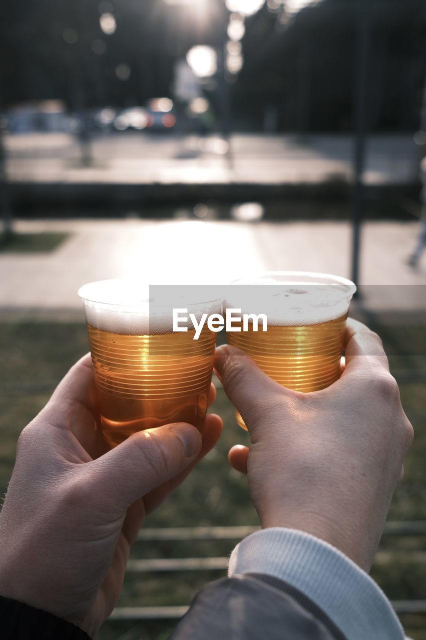 CROPPED IMAGE OF HAND HOLDING GLASS OF BEER