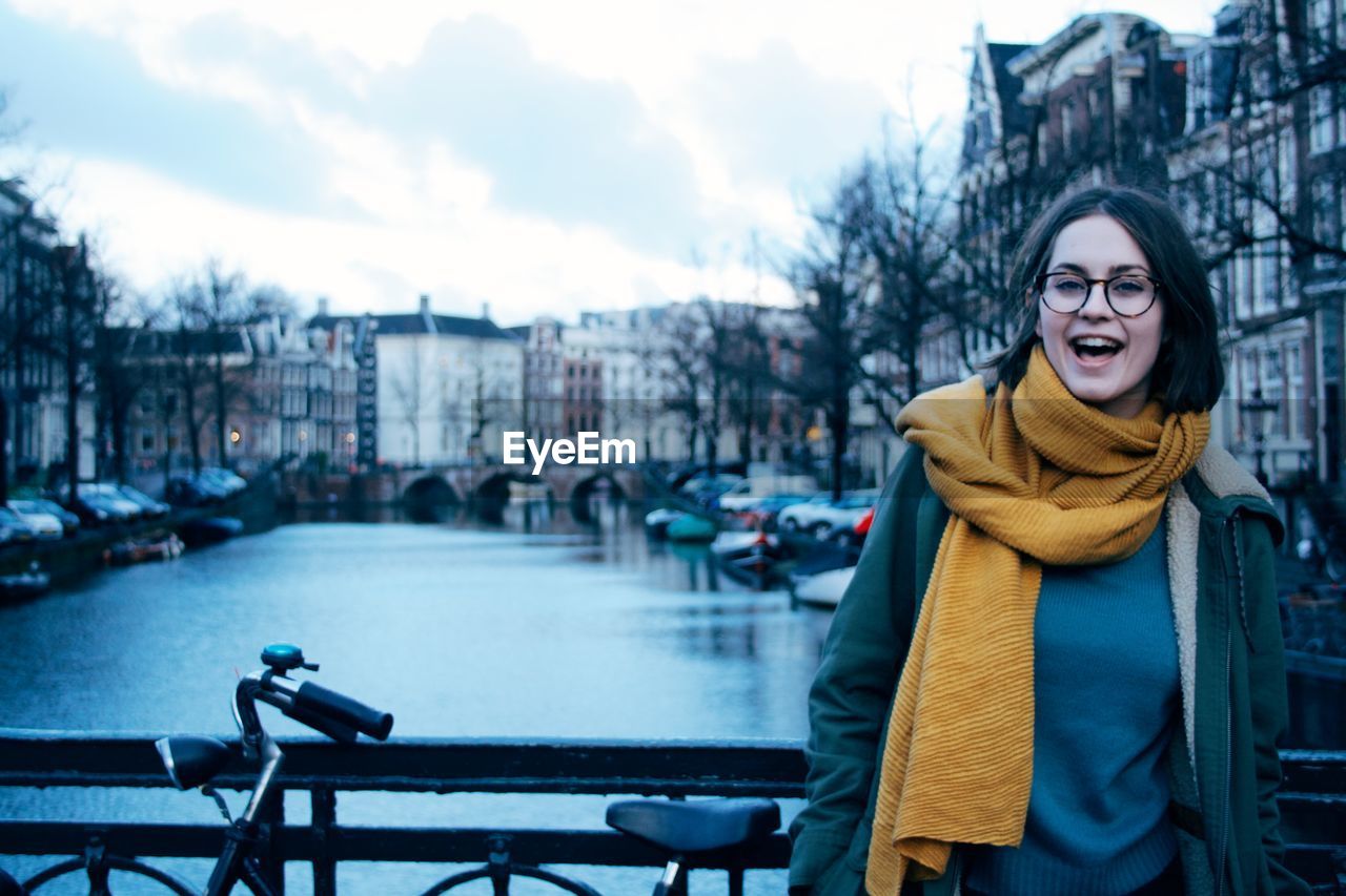 Portrait of smiling young woman standing by railing