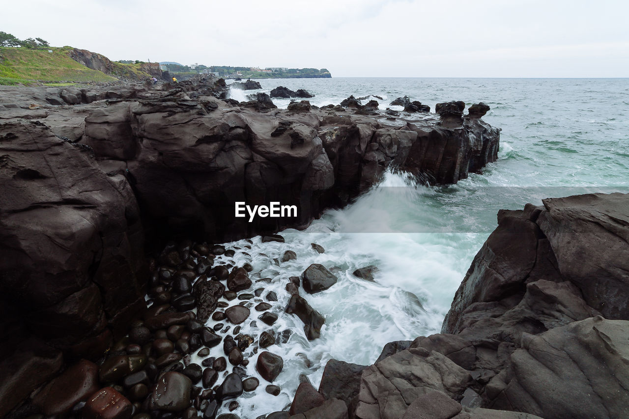 ROCKS ON SEA AGAINST SKY