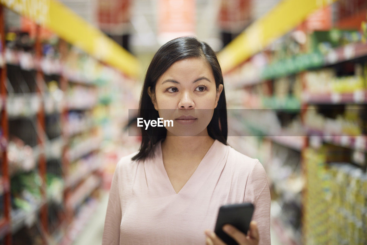 Woman looking at prices during inflation while doing shopping in supermarket