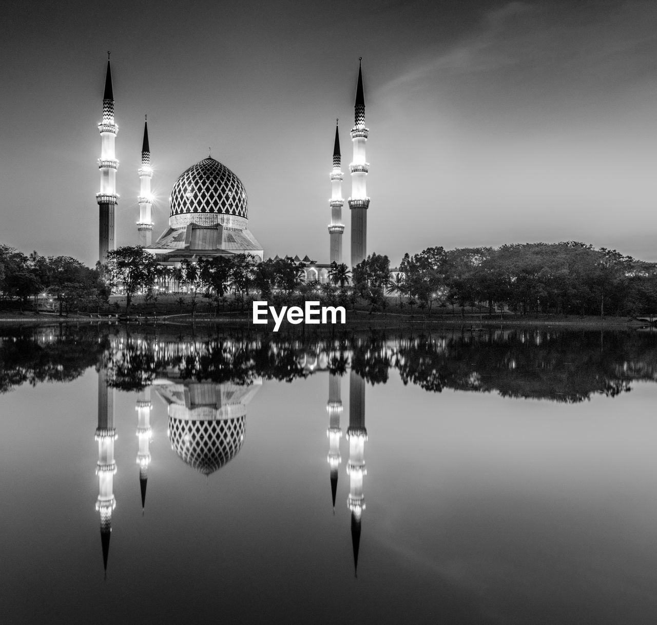 REFLECTION OF ILLUMINATED TOWER IN CITY AGAINST SKY