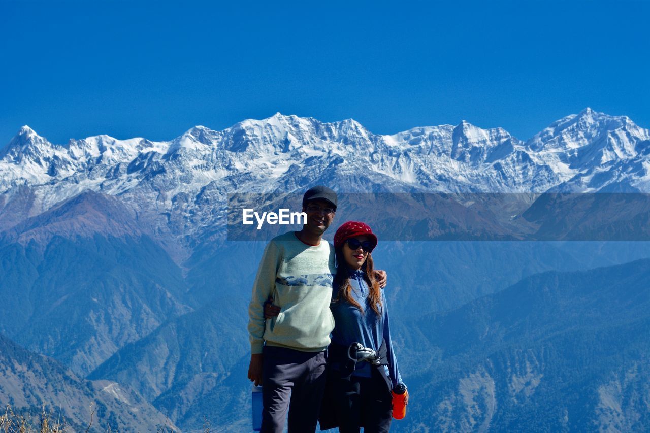 Portrait of couple standing against snowcapped mountains
