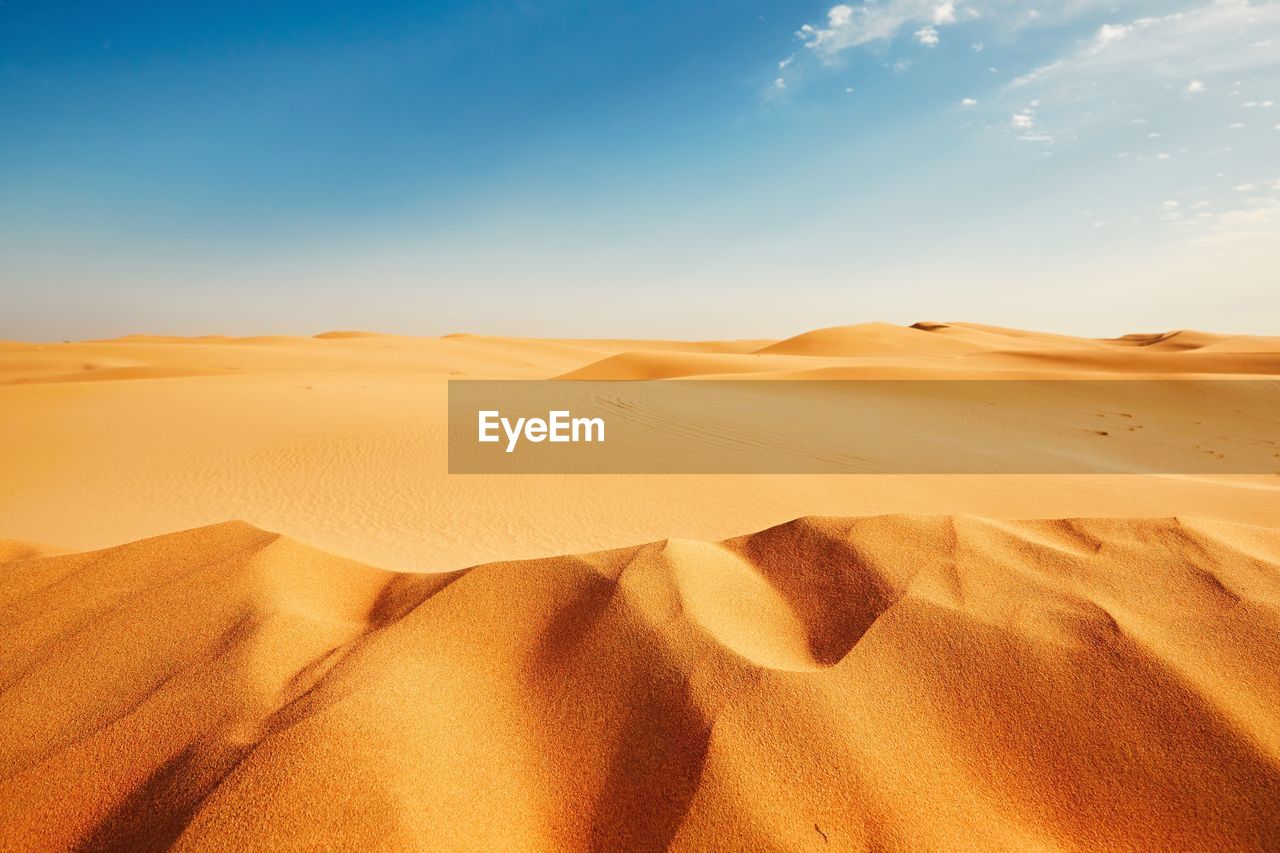 Sand dunes in desert against sky