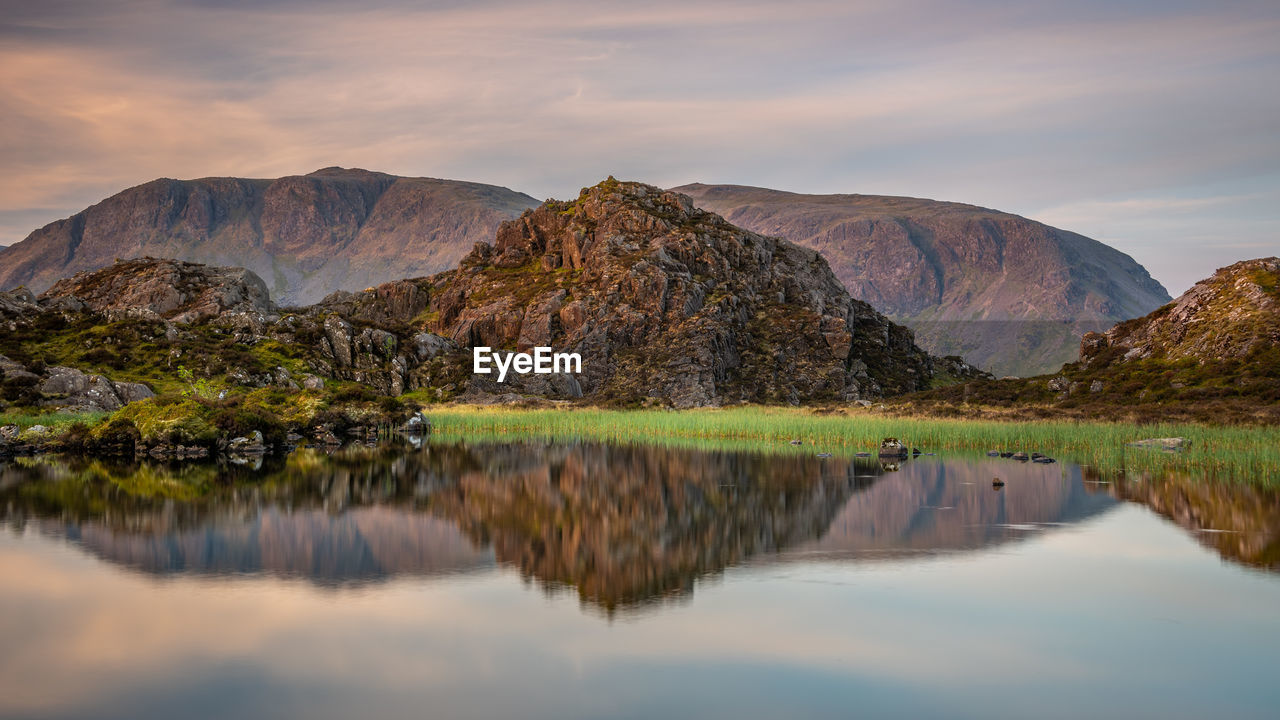 REFLECTION OF MOUNTAINS IN LAKE AGAINST SKY