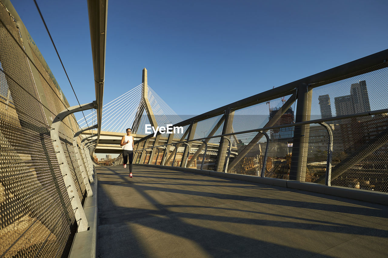 A woman runs near the zakim bridge in boston.