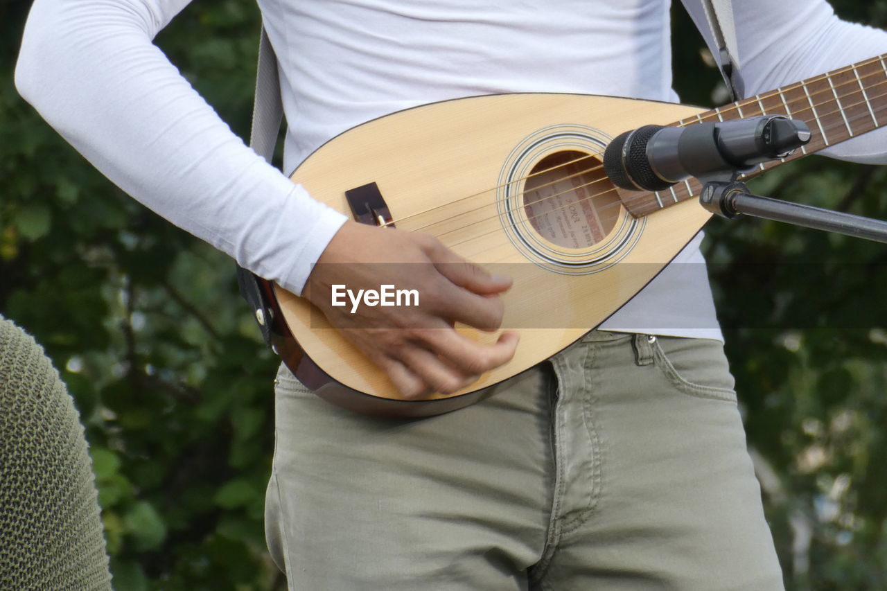 Midsection of man playing guitar