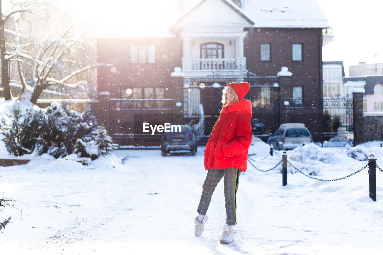 Young stylish blonde woman on the street has fun, posing in snowy, frosty