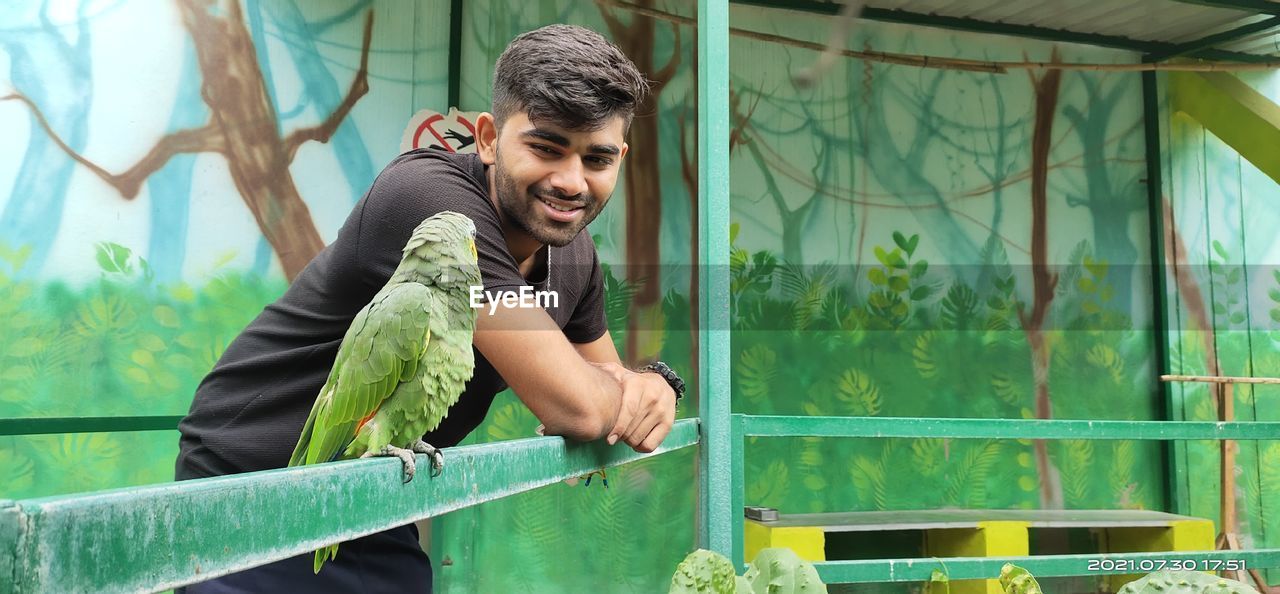 Young man and parrot looking at each other...