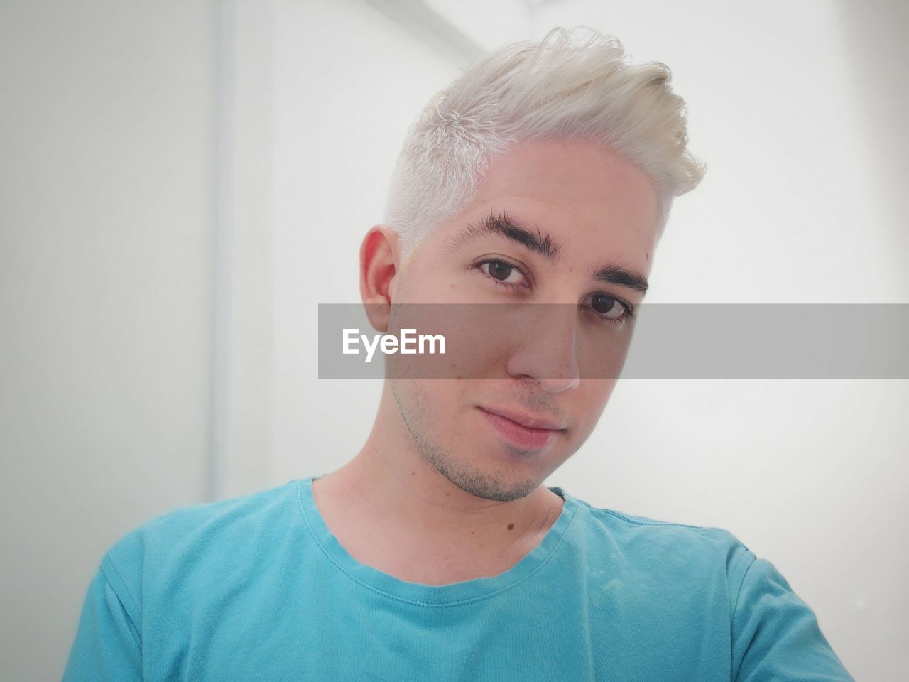 Close-up portrait of young man with dyed hair at home