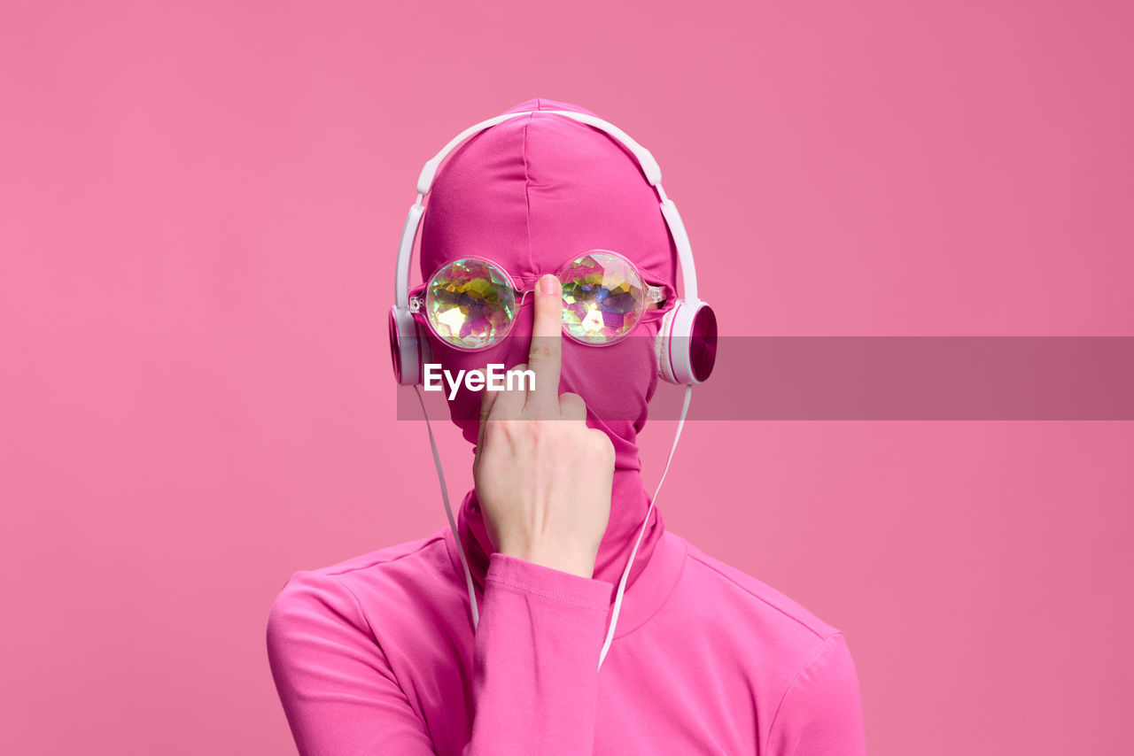 portrait of young woman wearing sunglasses against pink background
