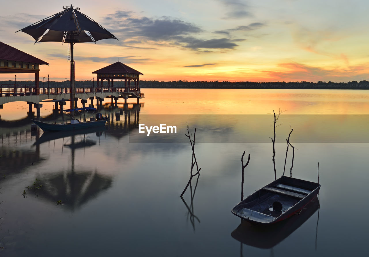 STILT HOUSE IN SWIMMING POOL AGAINST SKY DURING SUNSET