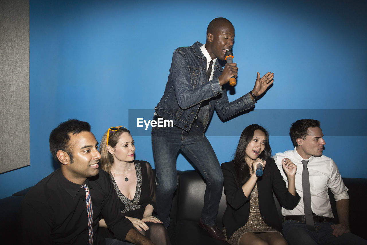 Cheerful friends singing karaoke in nightclub