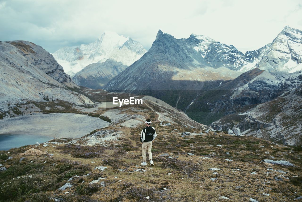 FULL LENGTH REAR VIEW OF MAN STANDING ON MOUNTAIN