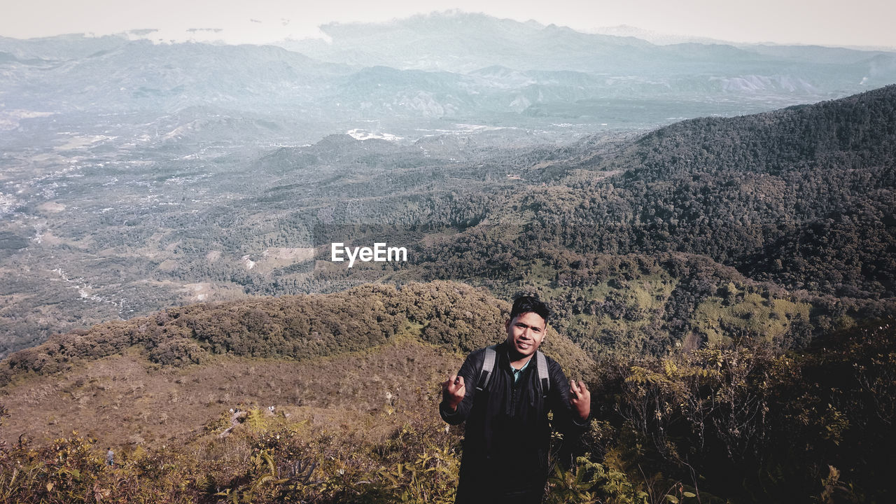 Young man standing against landscape