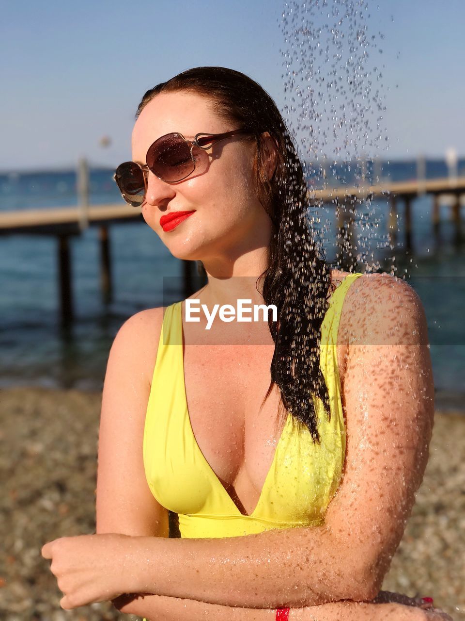 Woman in swimwear talking shower at beach