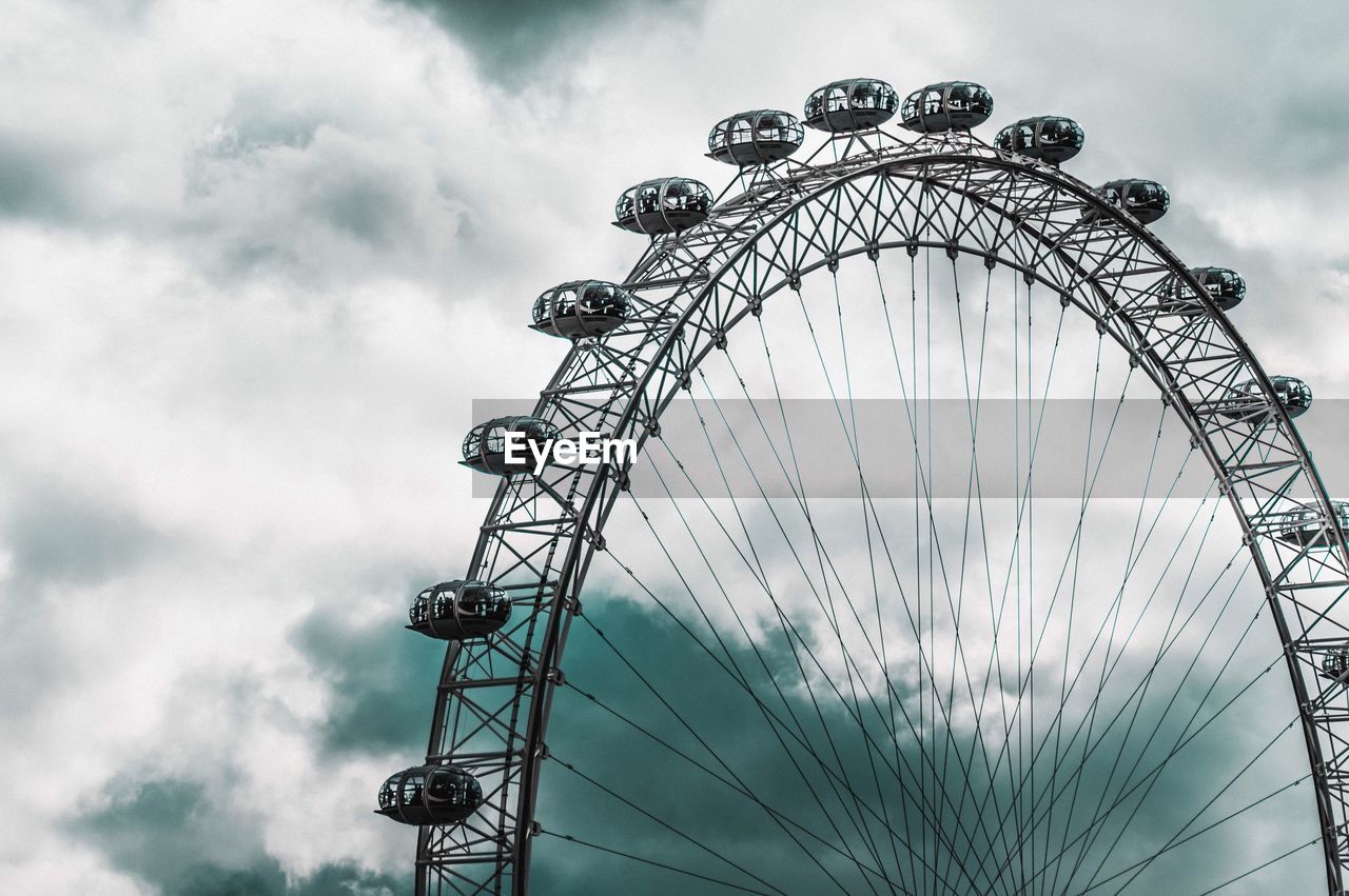 Low angle view of ferris wheel against cloudy sky