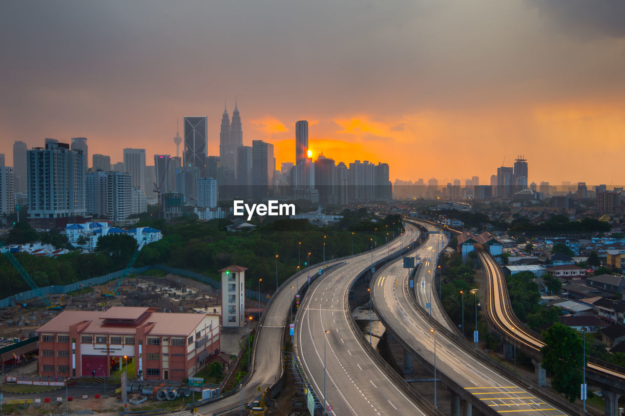 Distant view of petronas towers against sky during sunset in city
