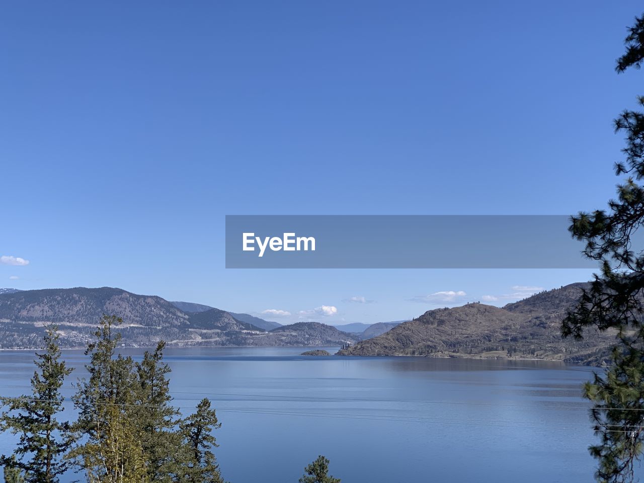 Scenic view of lake and mountains against clear blue sky