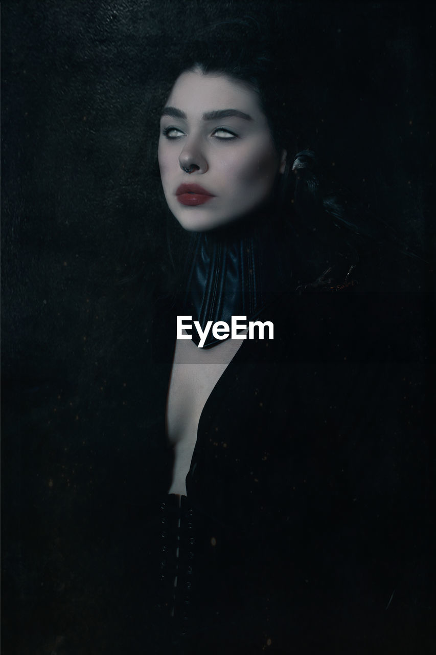 PORTRAIT OF BEAUTIFUL YOUNG WOMAN OVER BLACK BACKGROUND