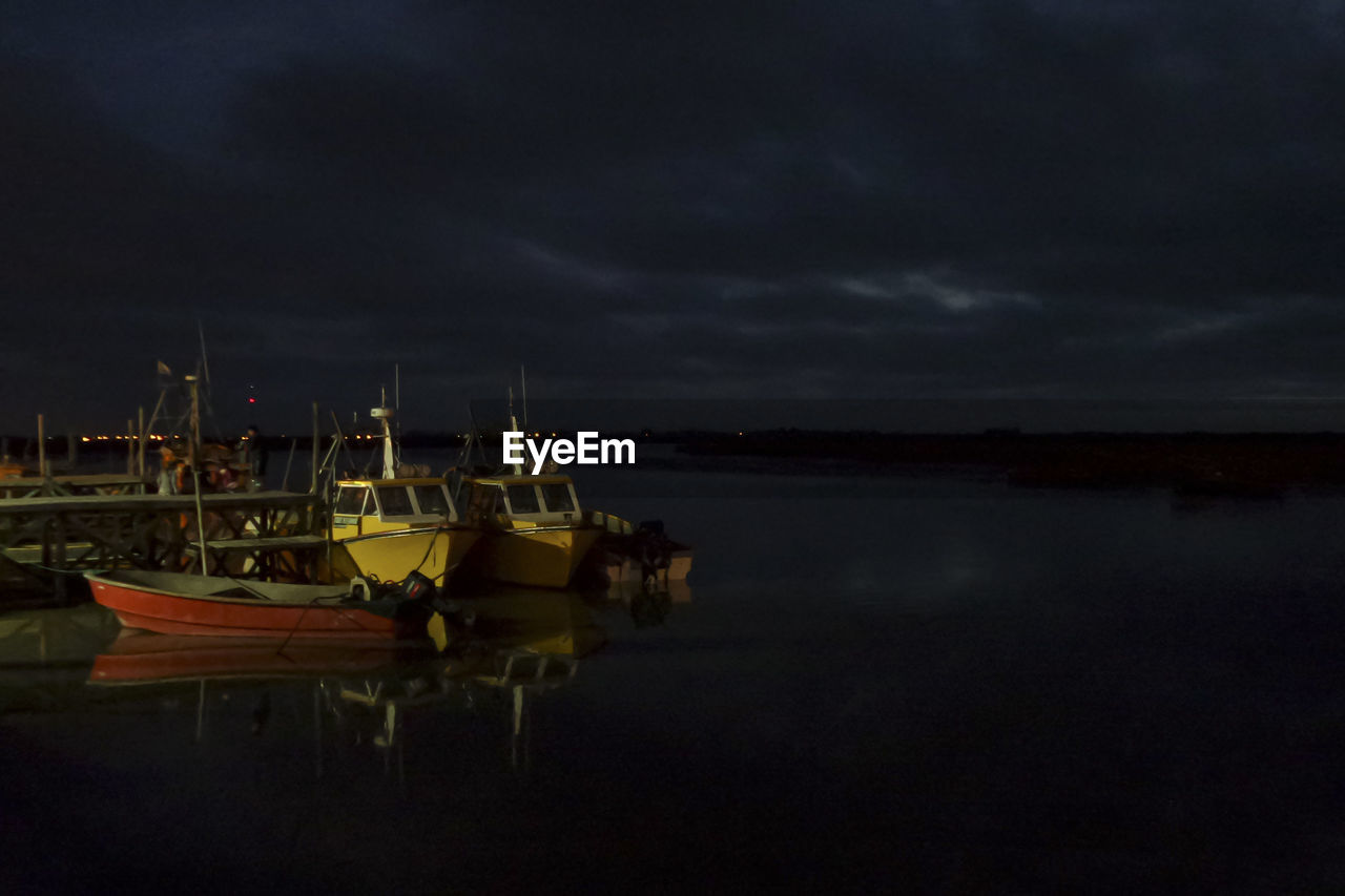 BOATS MOORED AT HARBOR DURING SUNSET