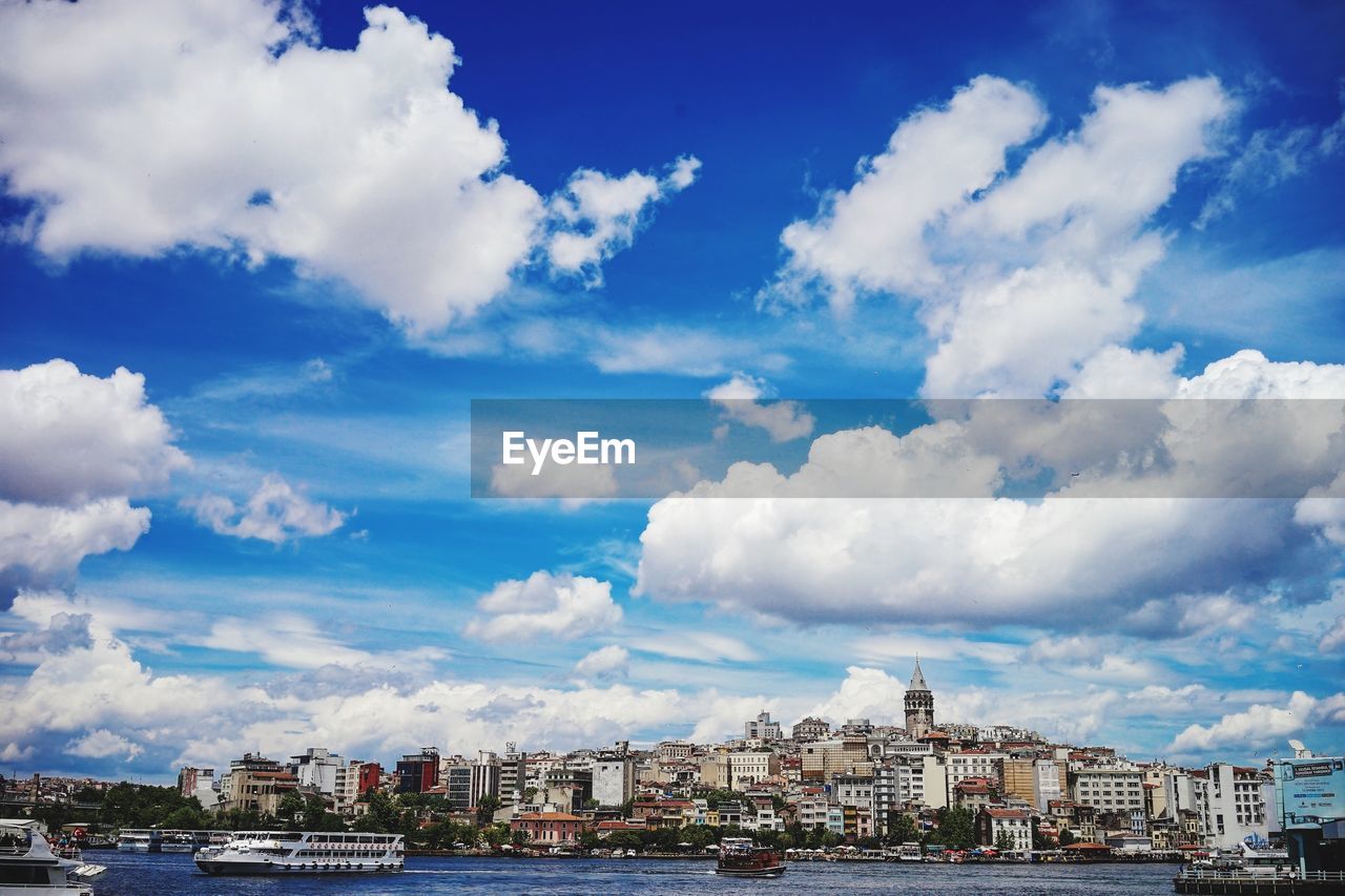 Residential district by river against cloudy sky