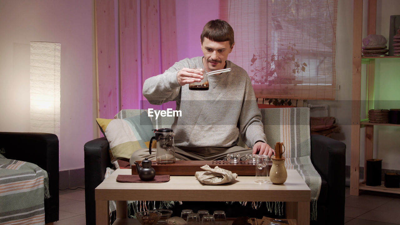 Man pouring coffee in cup at home