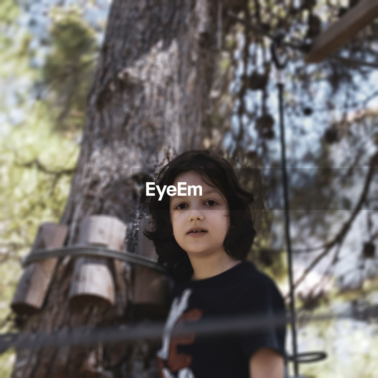 Portrait of teenage boy standing against tree