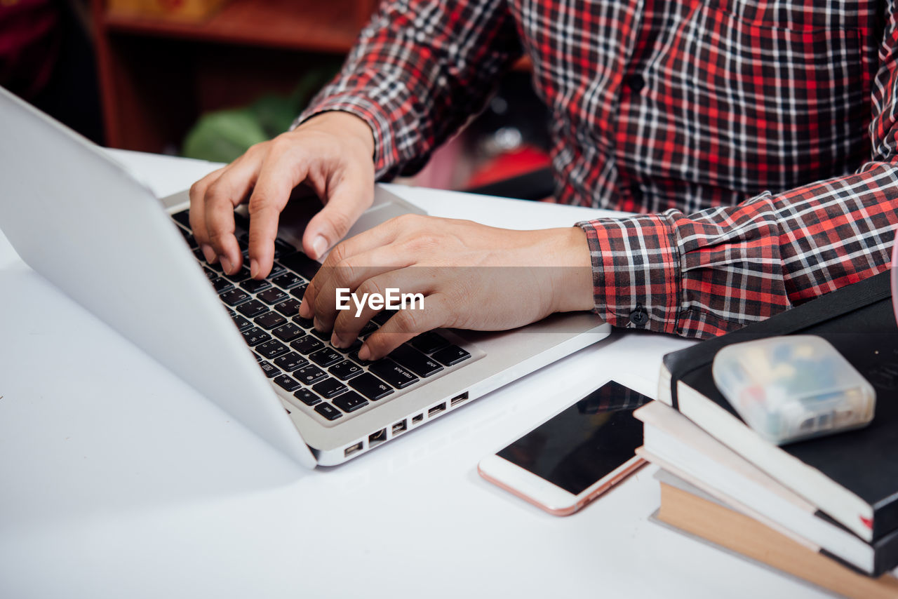 MIDSECTION OF MAN USING LAPTOP