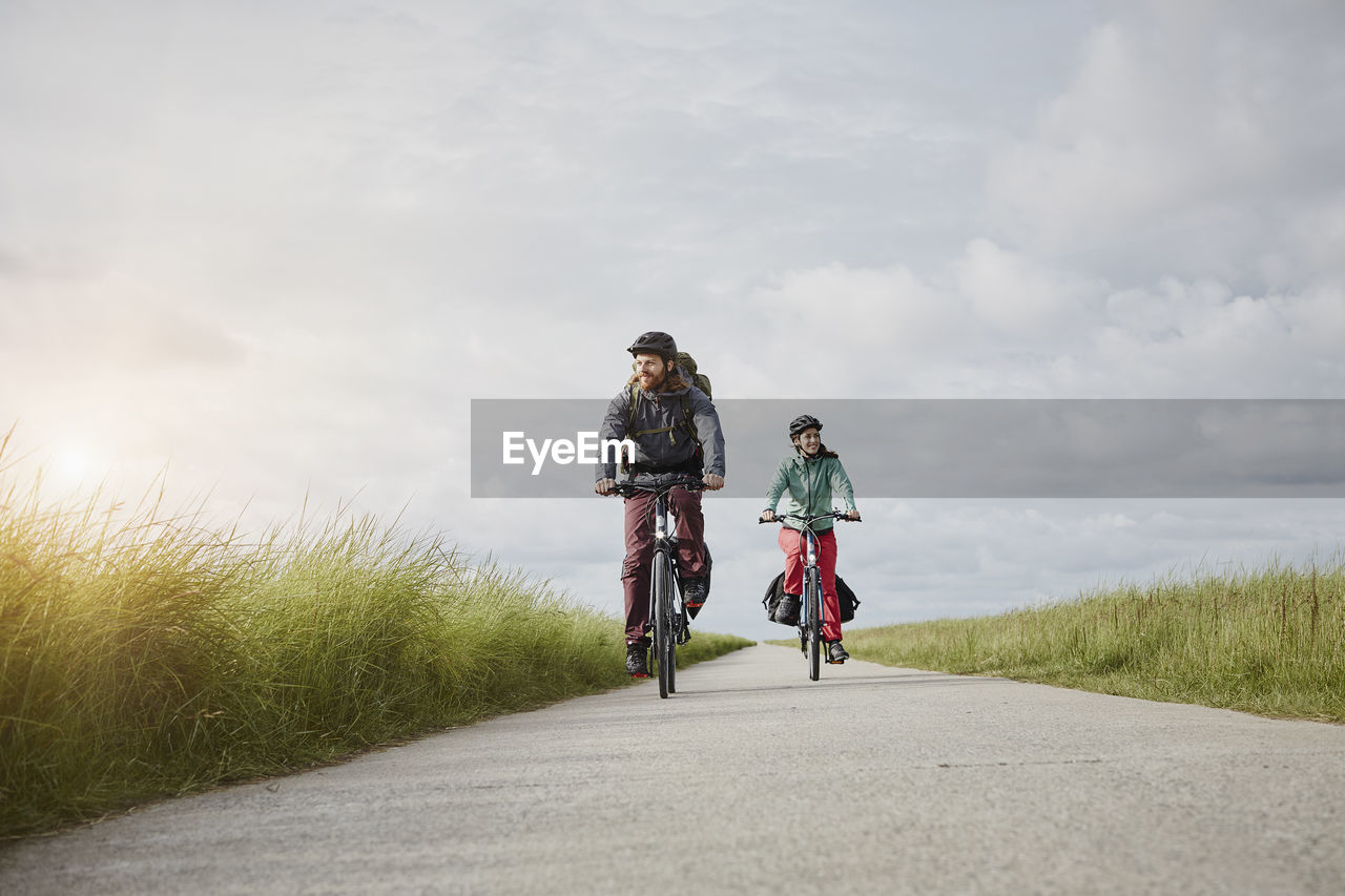 Germany, schleswig-holstein, eiderstedt, couple riding bicycle on path through salt marsh