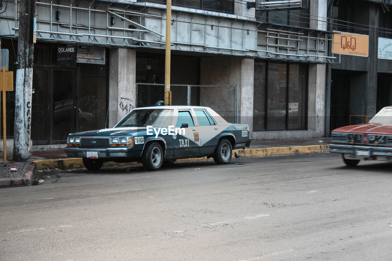 CAR PARKED ON ROAD AGAINST BUILDINGS