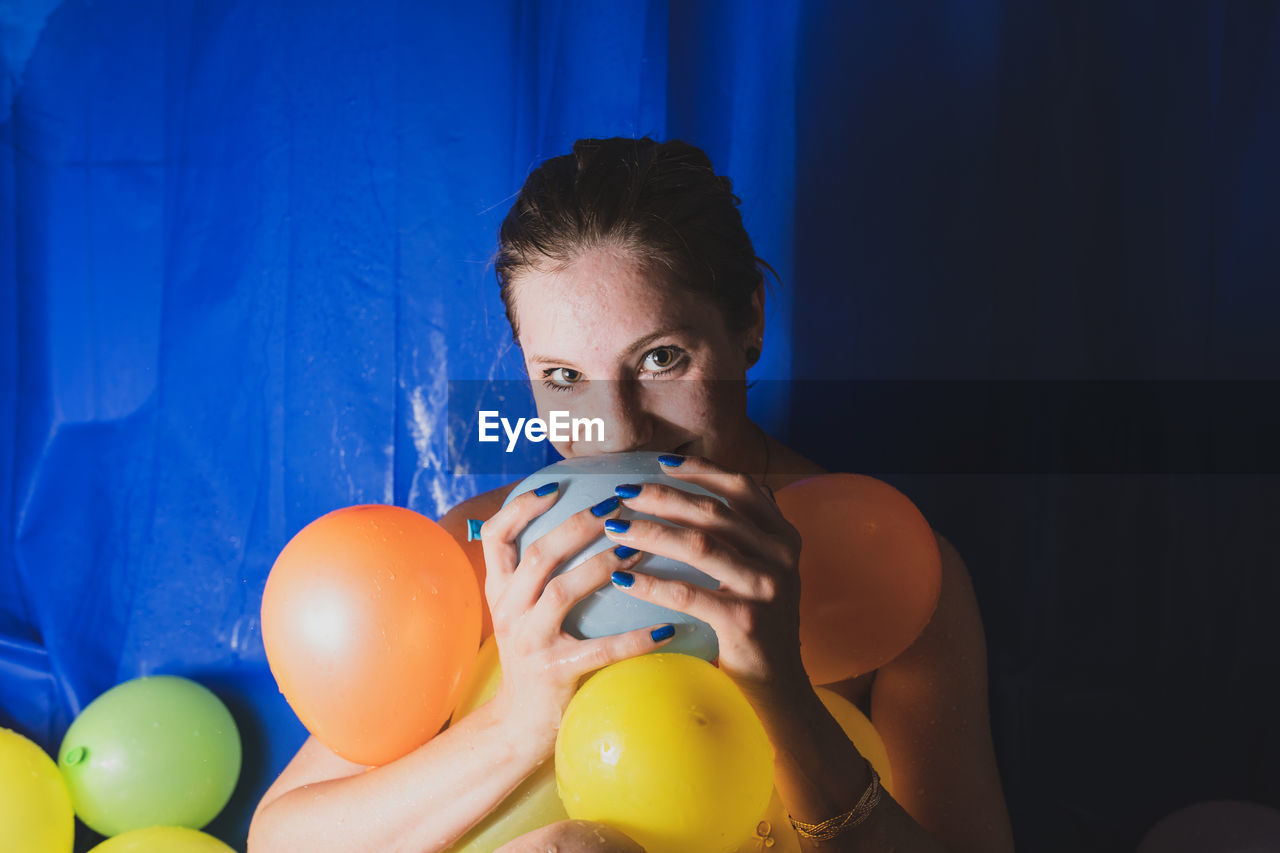 Portrait of woman with colorful balloons at home