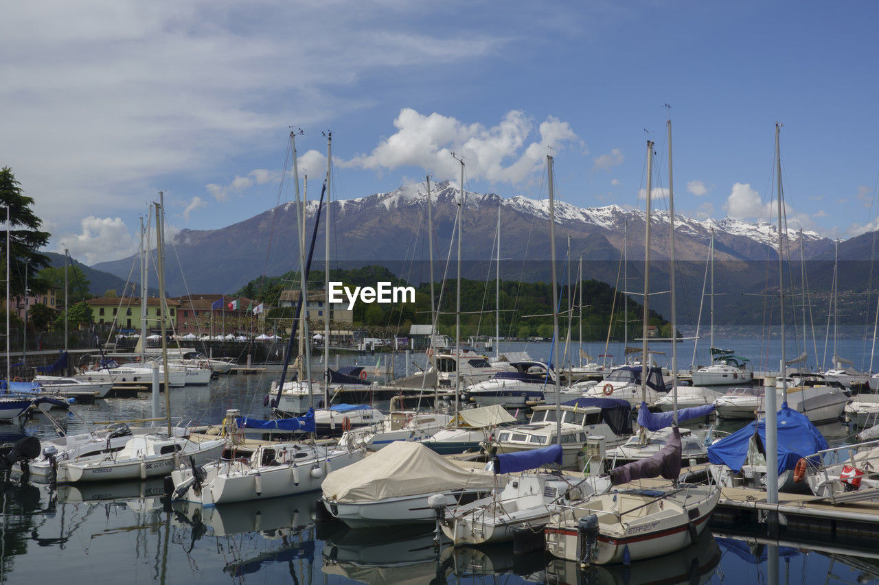 boats moored at harbor against cloudy sky