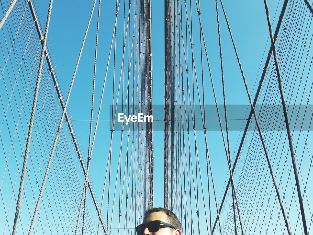 Low angle view of man on bridge against blue sky