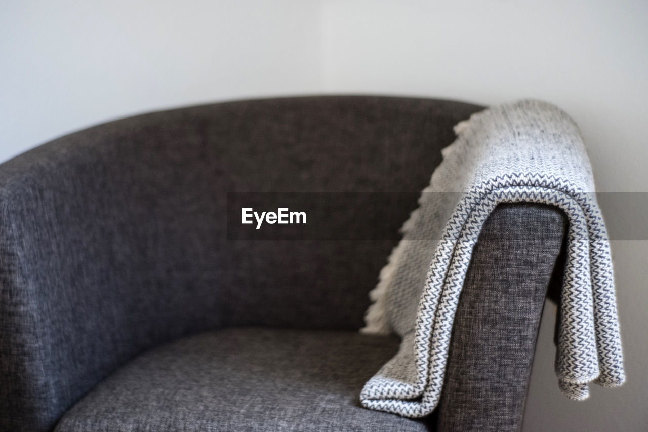 Close-up of shawl on armchair against wall at home