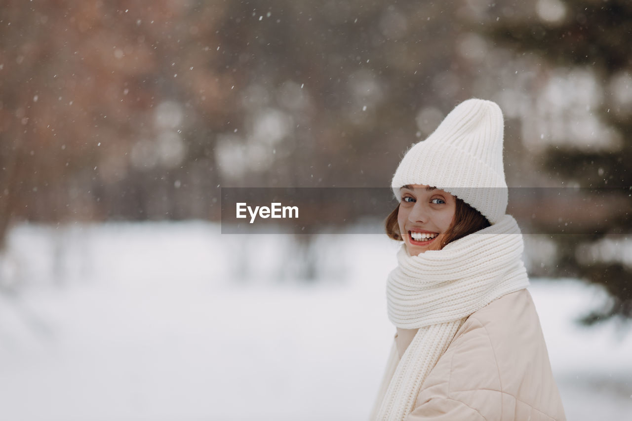 portrait of young woman standing on snow covered field during winter