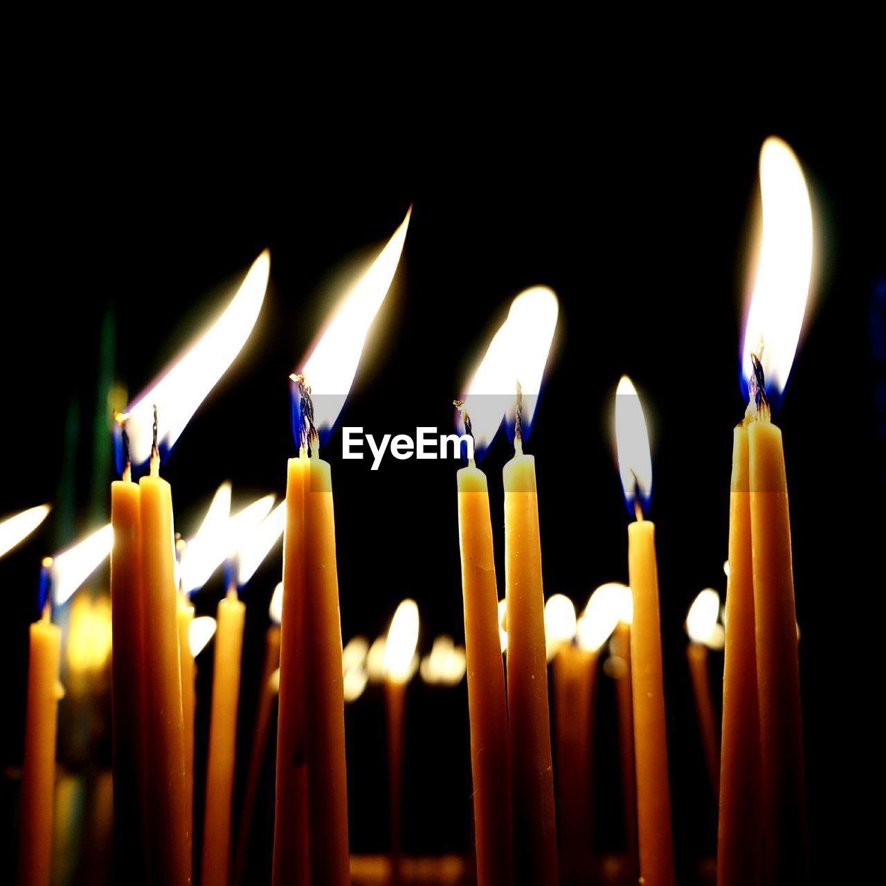Close-up of lit candles over black background