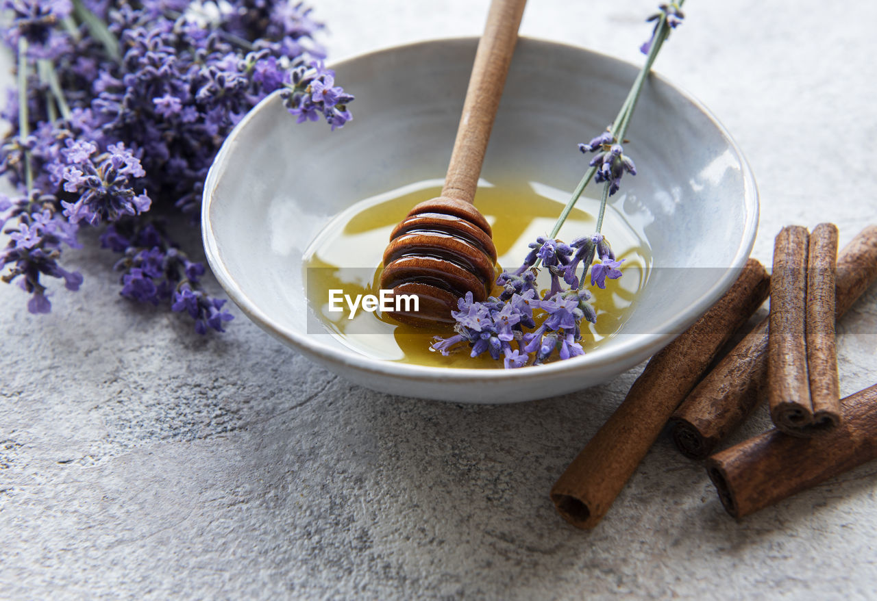 Bowl with honey and fresh lavender flowers on a concrete background